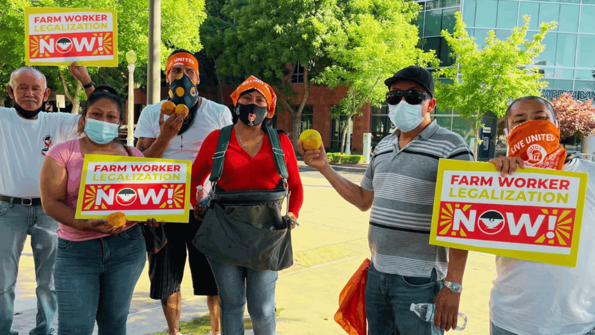 Several individuals in masks, standing together and displaying signs, showing solidarity for a social movement.