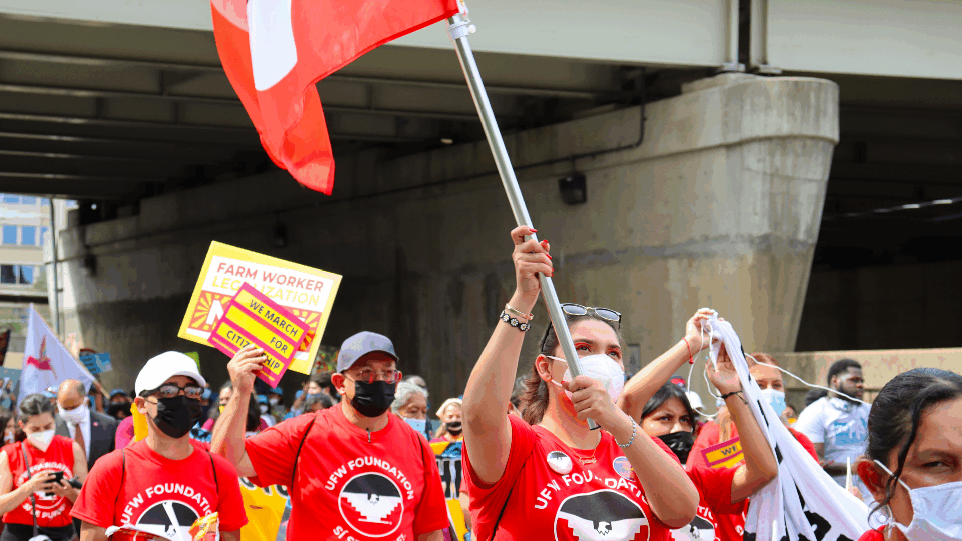 Several individuals with red flags and signs, united in a demonstration or public gathering.
