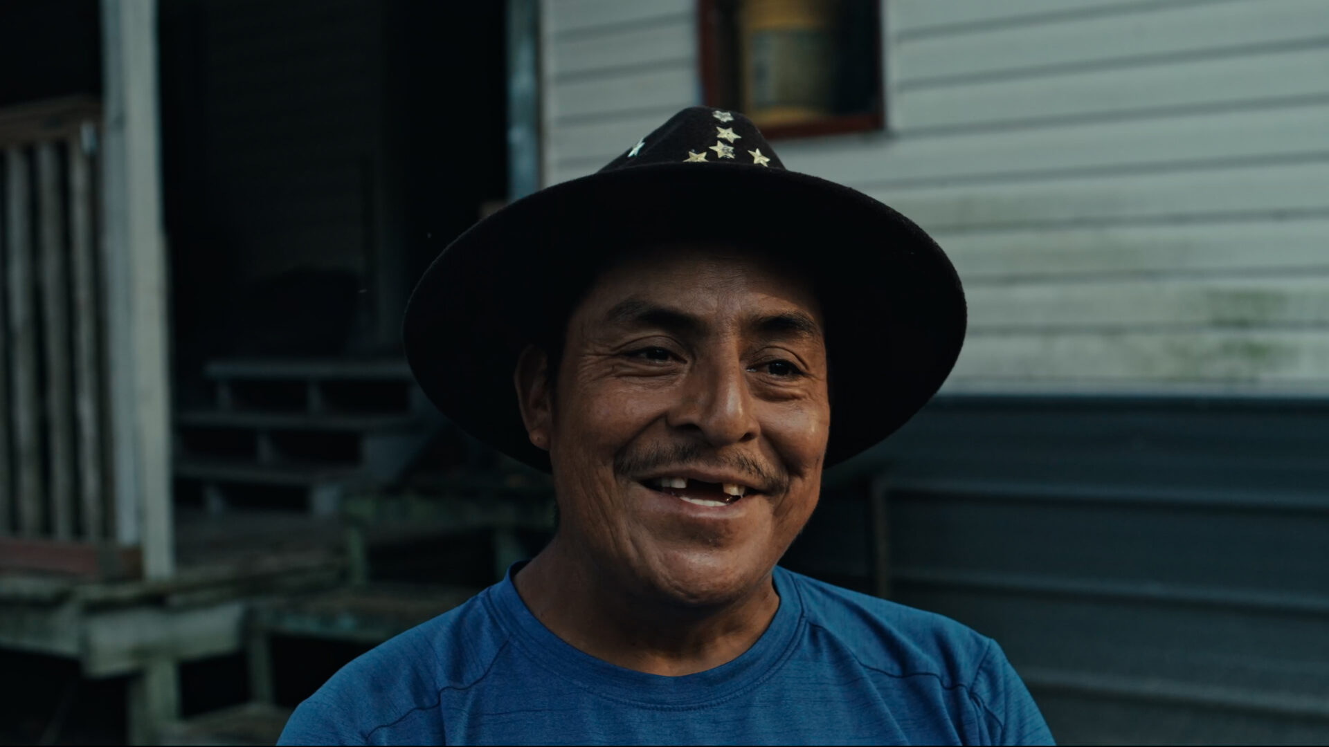 A smiling man wearing a hat looks directly at the camera.