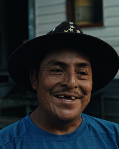 A smiling man wearing a hat looks directly at the camera.